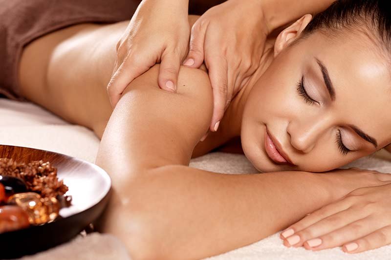 A person receiving a massage on a spa table next to a wooden bowl, one of many bed and breakfast add ons in Columbia, TN.